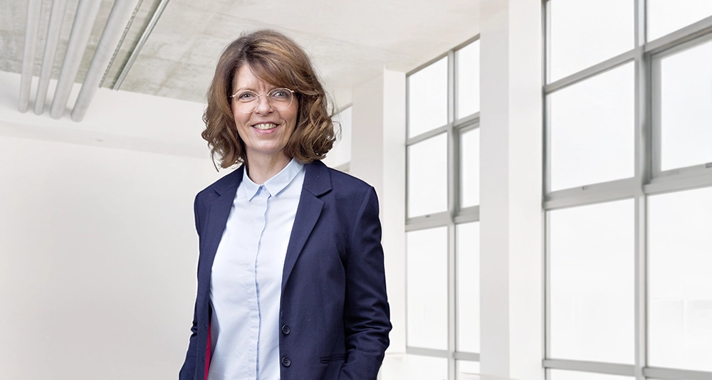 Gabriele Aumeier in einem Hellen Raum mit Fensterfront.